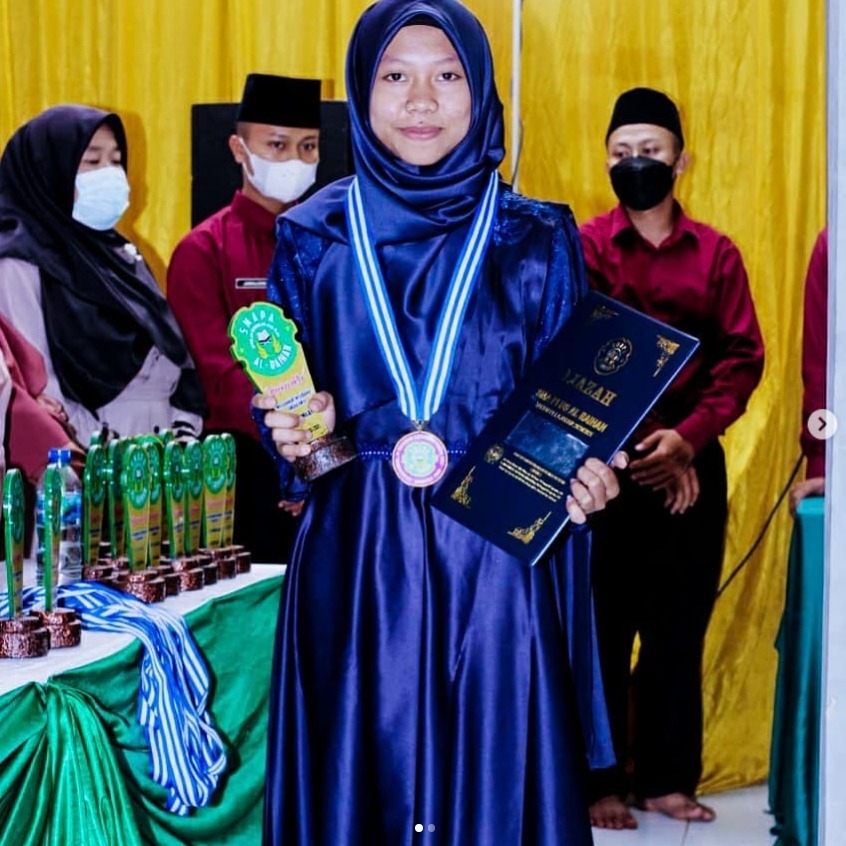 Milaa holding a trophy and certificate